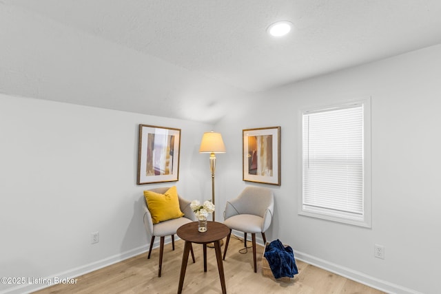 sitting room with baseboards, light wood-style floors, and vaulted ceiling