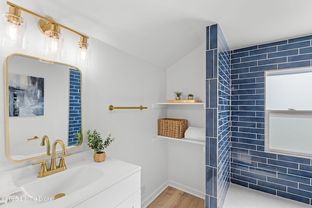 full bathroom with vanity, vaulted ceiling, wood finished floors, and walk in shower