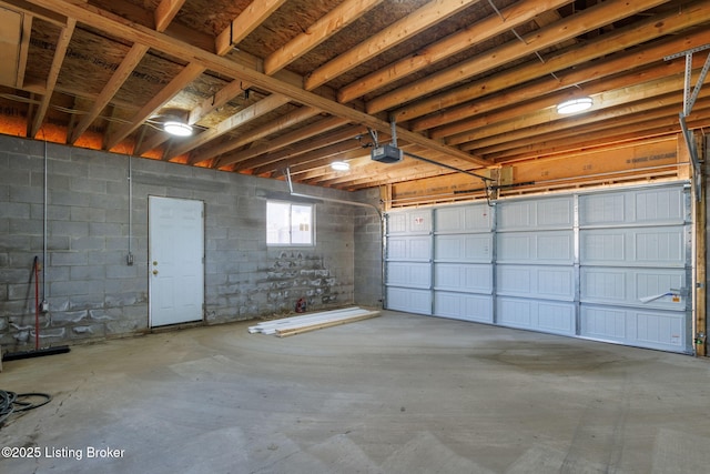 garage with a garage door opener and concrete block wall