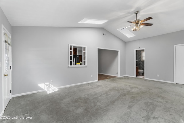 interior space with baseboards, connected bathroom, lofted ceiling with skylight, black refrigerator, and carpet