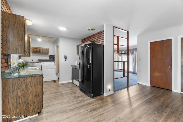 kitchen featuring baseboards, dark countertops, washer / clothes dryer, light wood-style floors, and black fridge