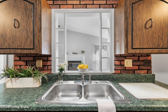 kitchen with dark countertops, a glass covered fireplace, and a sink