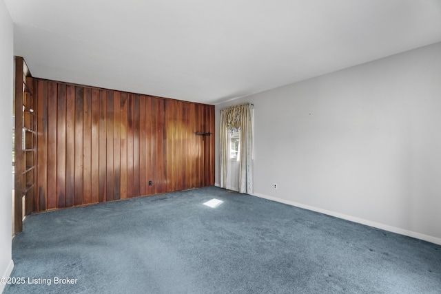 carpeted empty room featuring wooden walls