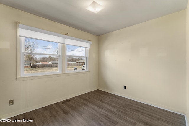 empty room featuring dark wood-style floors, visible vents, and baseboards