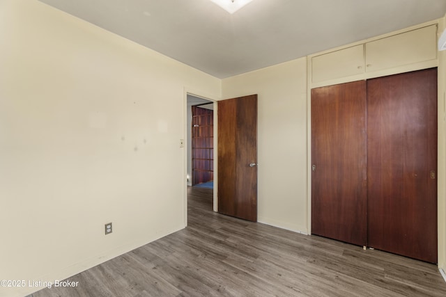 unfurnished bedroom with a closet, baseboards, and wood finished floors