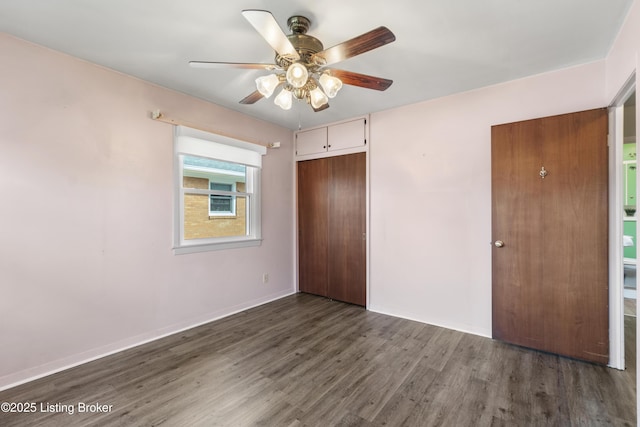 unfurnished bedroom with a closet, ceiling fan, baseboards, and wood finished floors