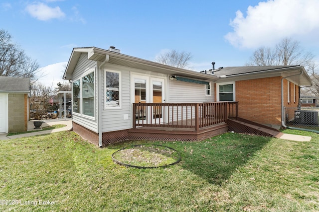 rear view of property with a deck, central AC, brick siding, fence, and a lawn