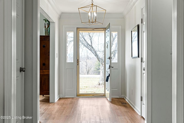 entryway featuring baseboards, an inviting chandelier, light wood-style flooring, and crown molding