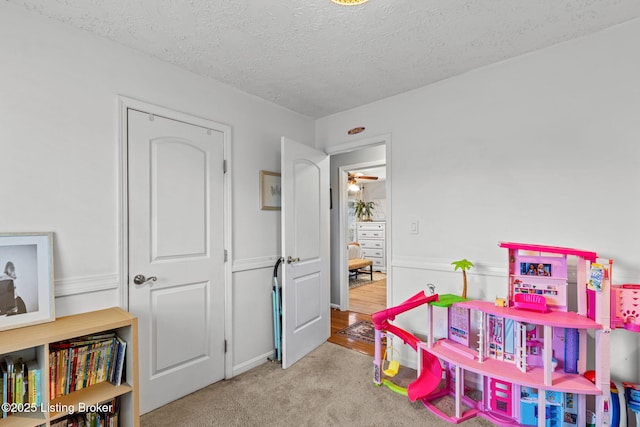 recreation room featuring carpet and a textured ceiling