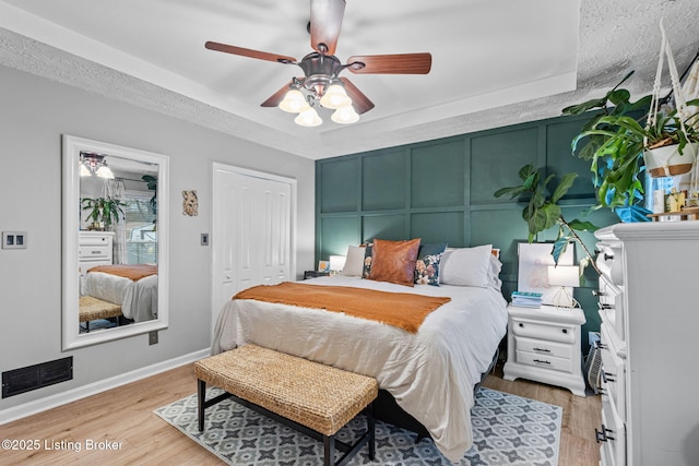 bedroom featuring baseboards, visible vents, ceiling fan, wood finished floors, and a closet