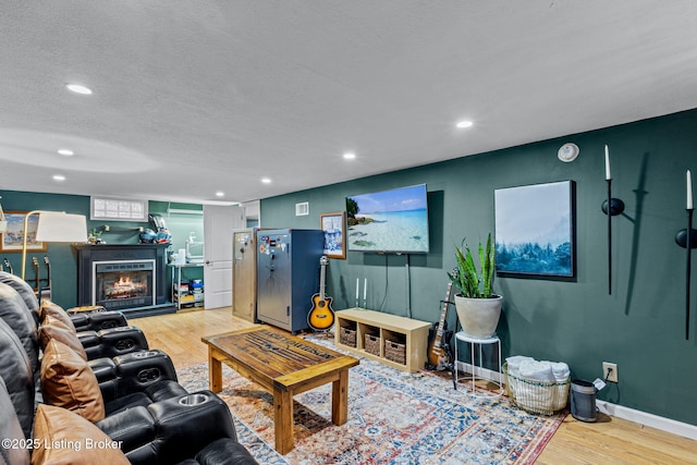 living room with a lit fireplace, wood finished floors, and recessed lighting