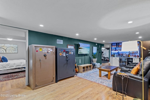 living area featuring recessed lighting, visible vents, a bar, wood finished floors, and beverage cooler