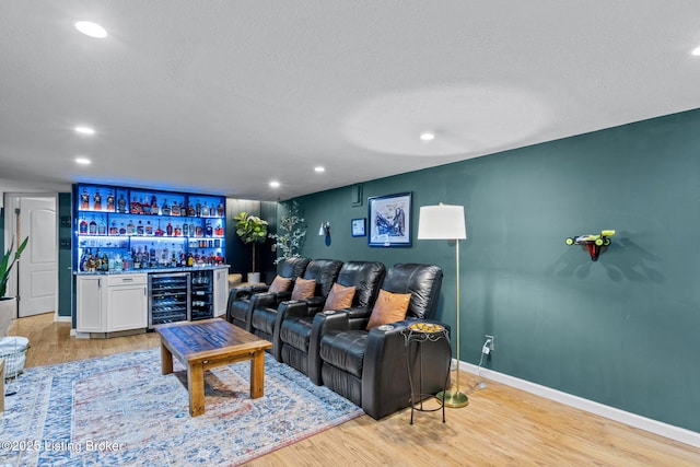 living area featuring baseboards, light wood-type flooring, wine cooler, a bar, and recessed lighting