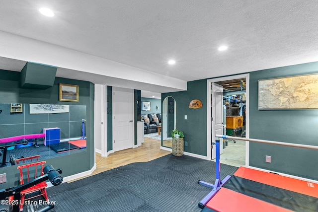 exercise area with arched walkways, baseboards, and recessed lighting