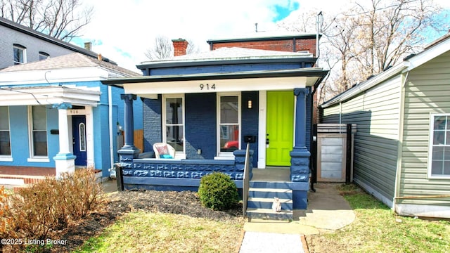 exterior space with a porch, brick siding, and a chimney