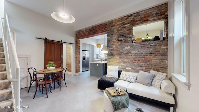 living room with stairway, brick wall, and a barn door