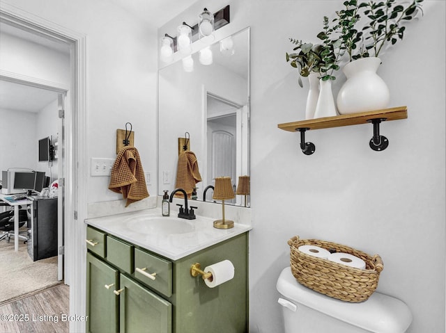 half bath featuring vanity, toilet, and wood finished floors