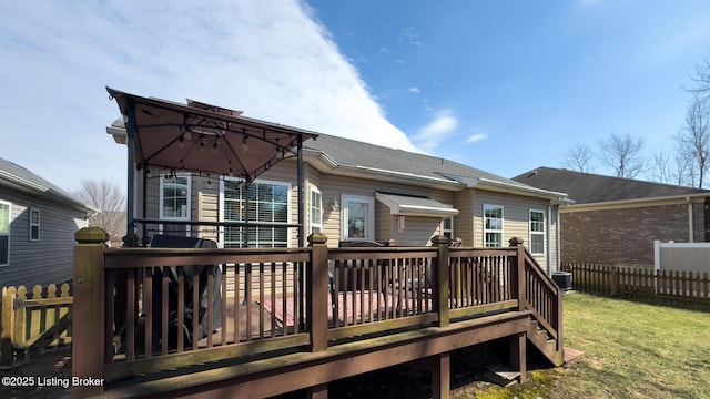 back of house with fence, a deck, and a lawn