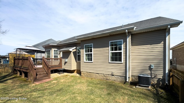 back of property with a lawn, a deck, central AC unit, and fence