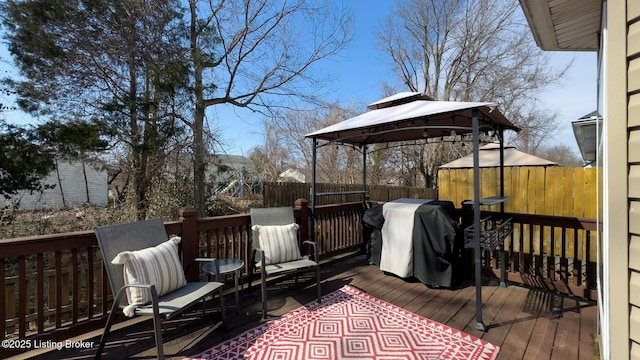 wooden terrace featuring fence, grilling area, and a gazebo