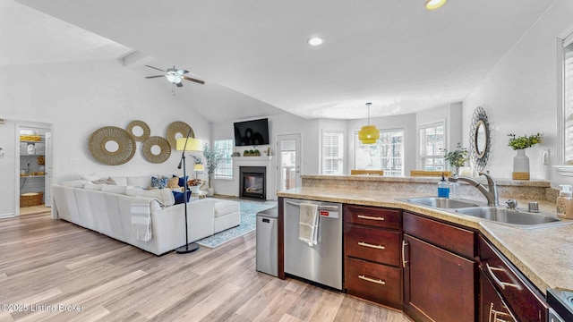 kitchen with light wood-style flooring, open floor plan, light countertops, stainless steel dishwasher, and a sink