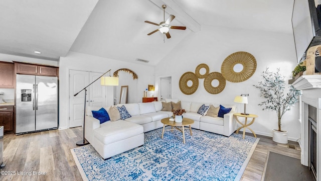 living room with visible vents, a fireplace with flush hearth, light wood-style floors, high vaulted ceiling, and beam ceiling