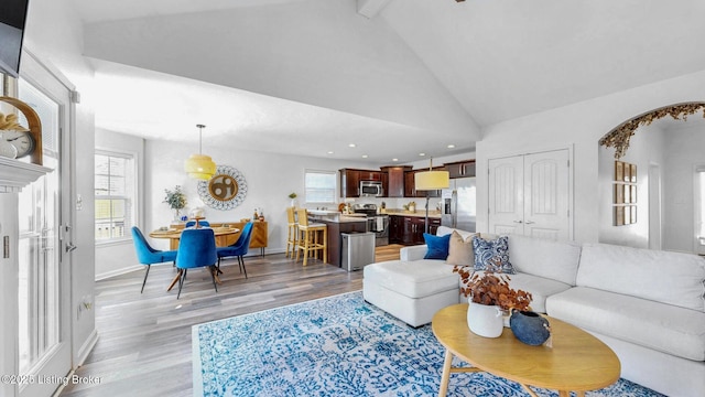 living room with beam ceiling, recessed lighting, high vaulted ceiling, light wood-type flooring, and baseboards