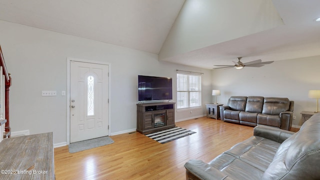 living area with baseboards, a fireplace, a ceiling fan, and light wood finished floors