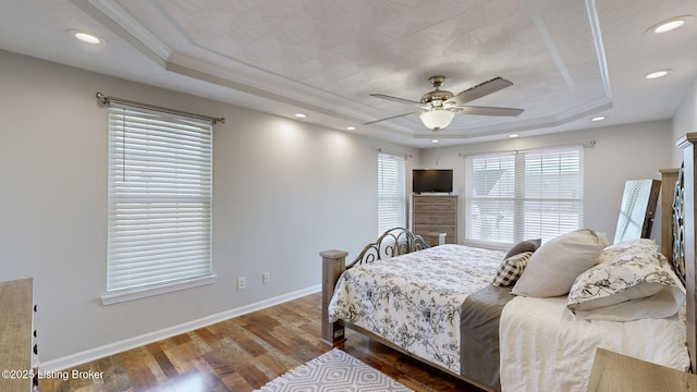 bedroom featuring crown molding, a raised ceiling, baseboards, and wood finished floors