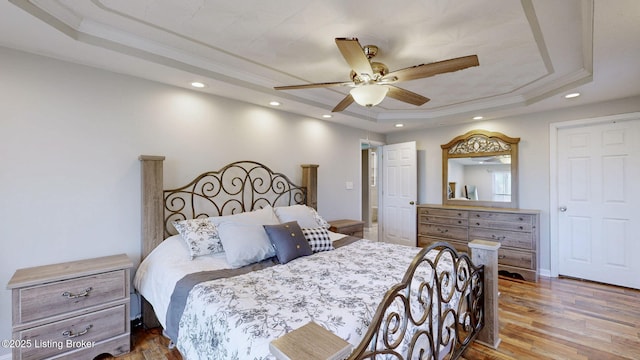 bedroom with recessed lighting, a raised ceiling, ornamental molding, and wood finished floors