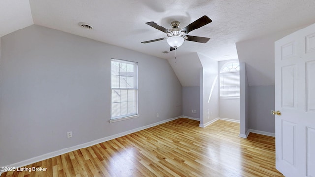 bonus room with visible vents, baseboards, lofted ceiling, light wood-style floors, and a textured ceiling