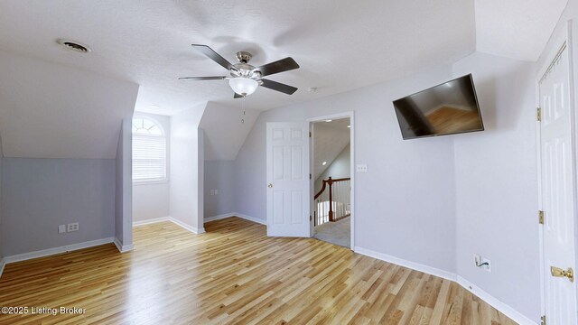 bonus room featuring visible vents, light wood-style flooring, a ceiling fan, baseboards, and lofted ceiling