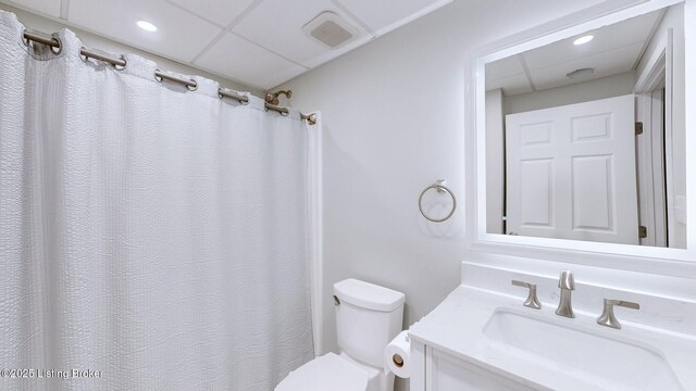 bathroom with visible vents, toilet, a shower with shower curtain, a paneled ceiling, and vanity