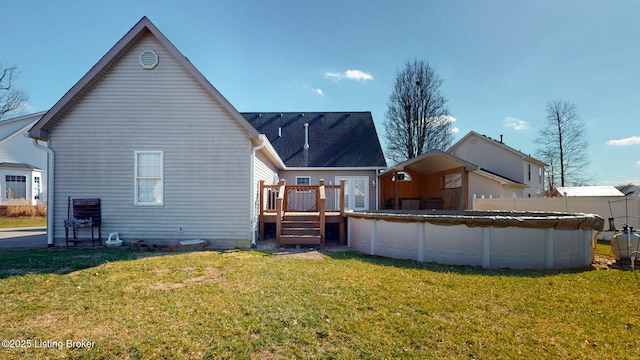 back of property featuring a wooden deck, a lawn, and a fenced in pool