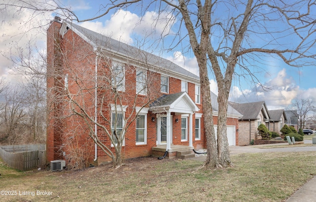 view of front of property featuring aphalt driveway, brick siding, a chimney, a garage, and a front lawn