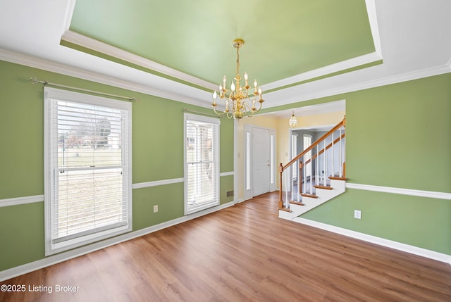 foyer featuring a raised ceiling, stairway, an inviting chandelier, and wood finished floors