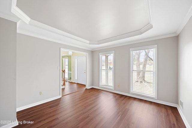 spare room with dark wood-style floors, a tray ceiling, stairway, and baseboards