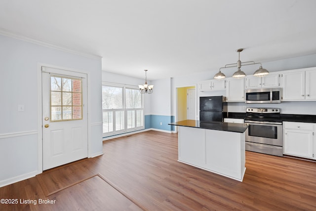 kitchen with appliances with stainless steel finishes, dark countertops, white cabinets, and wood finished floors