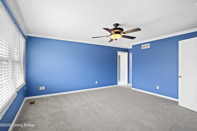 carpeted spare room featuring baseboards, visible vents, and crown molding