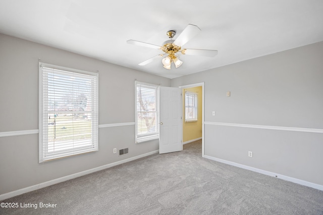 carpeted empty room with ceiling fan, visible vents, and baseboards