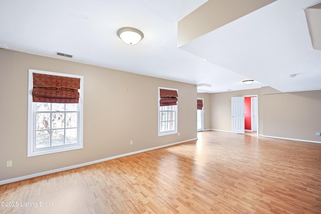 empty room featuring light wood-type flooring, baseboards, and visible vents