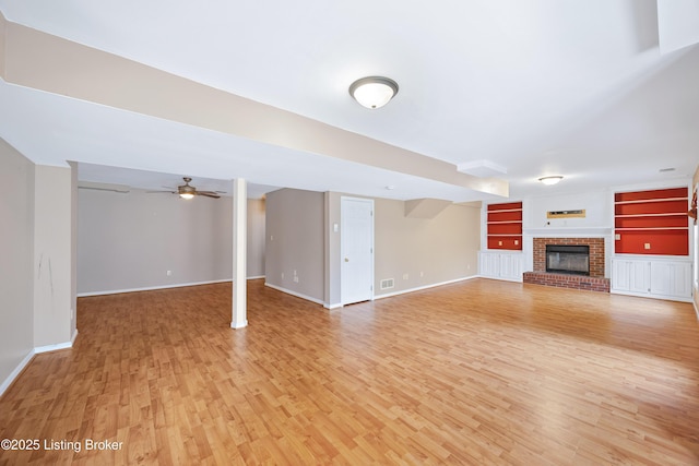 unfurnished living room featuring a brick fireplace, light wood-style flooring, and baseboards