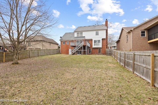 rear view of property featuring a lawn, a fenced backyard, a chimney, stairway, and brick siding