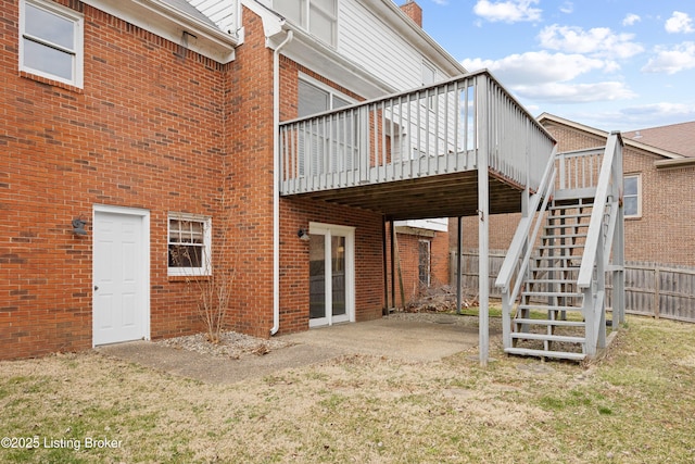 back of house featuring fence, stairway, and brick siding