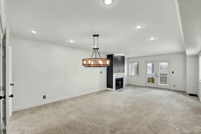 unfurnished living room with light carpet, recessed lighting, ornamental molding, and french doors