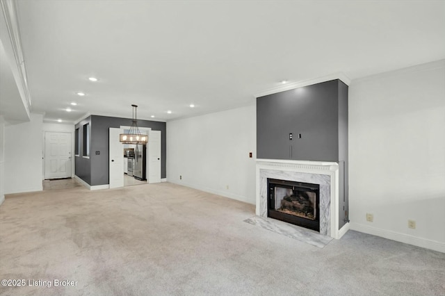 unfurnished living room with crown molding, a notable chandelier, recessed lighting, a premium fireplace, and light carpet