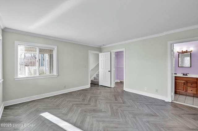 unfurnished bedroom featuring a sink, crown molding, ensuite bath, and baseboards