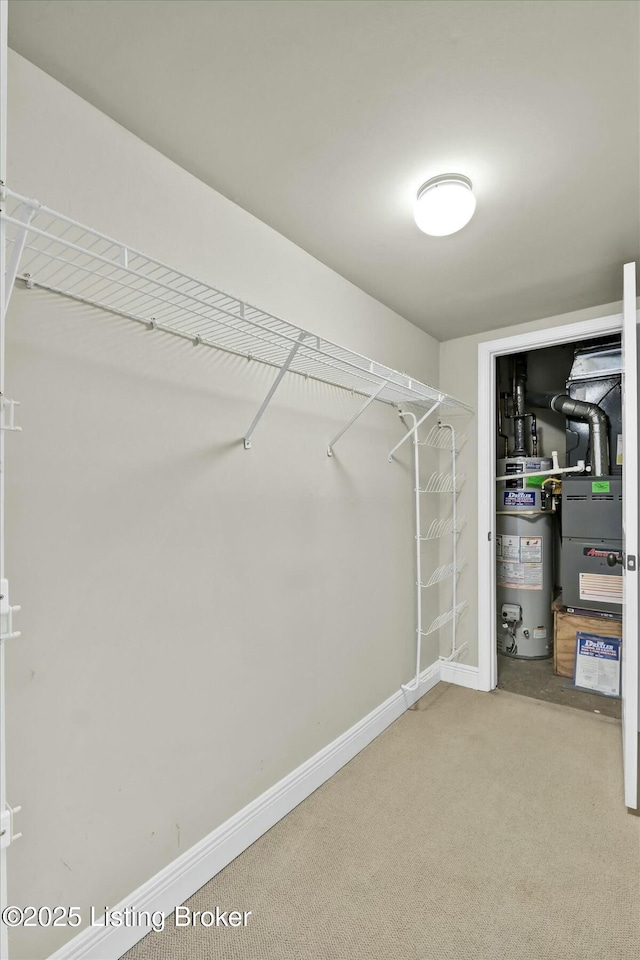 walk in closet with gas water heater, carpet flooring, and heating unit