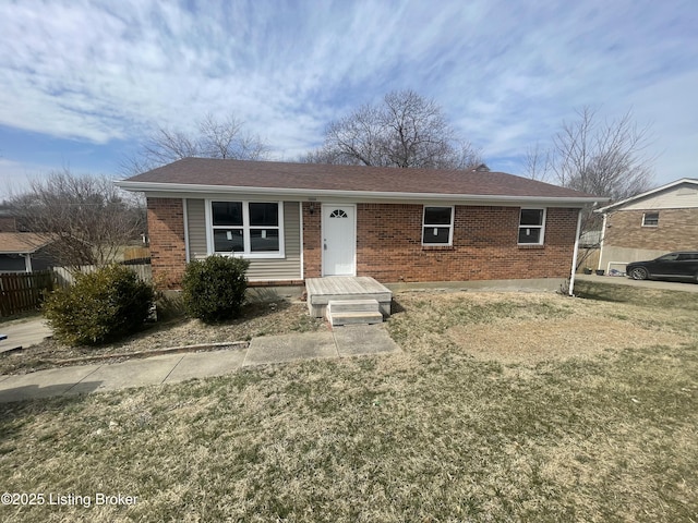 ranch-style home with brick siding, fence, and a front lawn