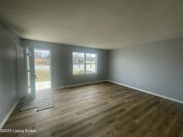 interior space with visible vents, a textured ceiling, baseboards, and wood finished floors